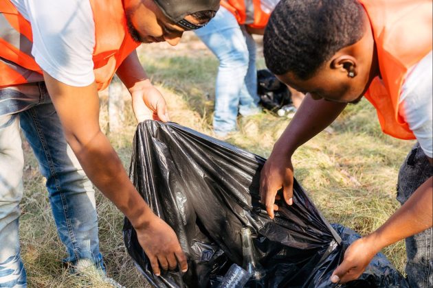 Volunteers holding black trash bag during park community cleanup