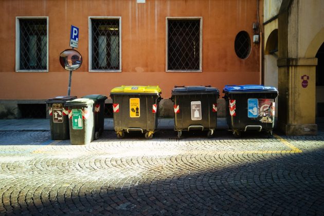 Color-coded recycling and waste dumpsters lined up on street