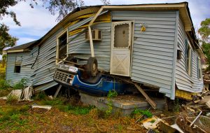 Overturned truck crushed under home highlighting disaster debris destruction